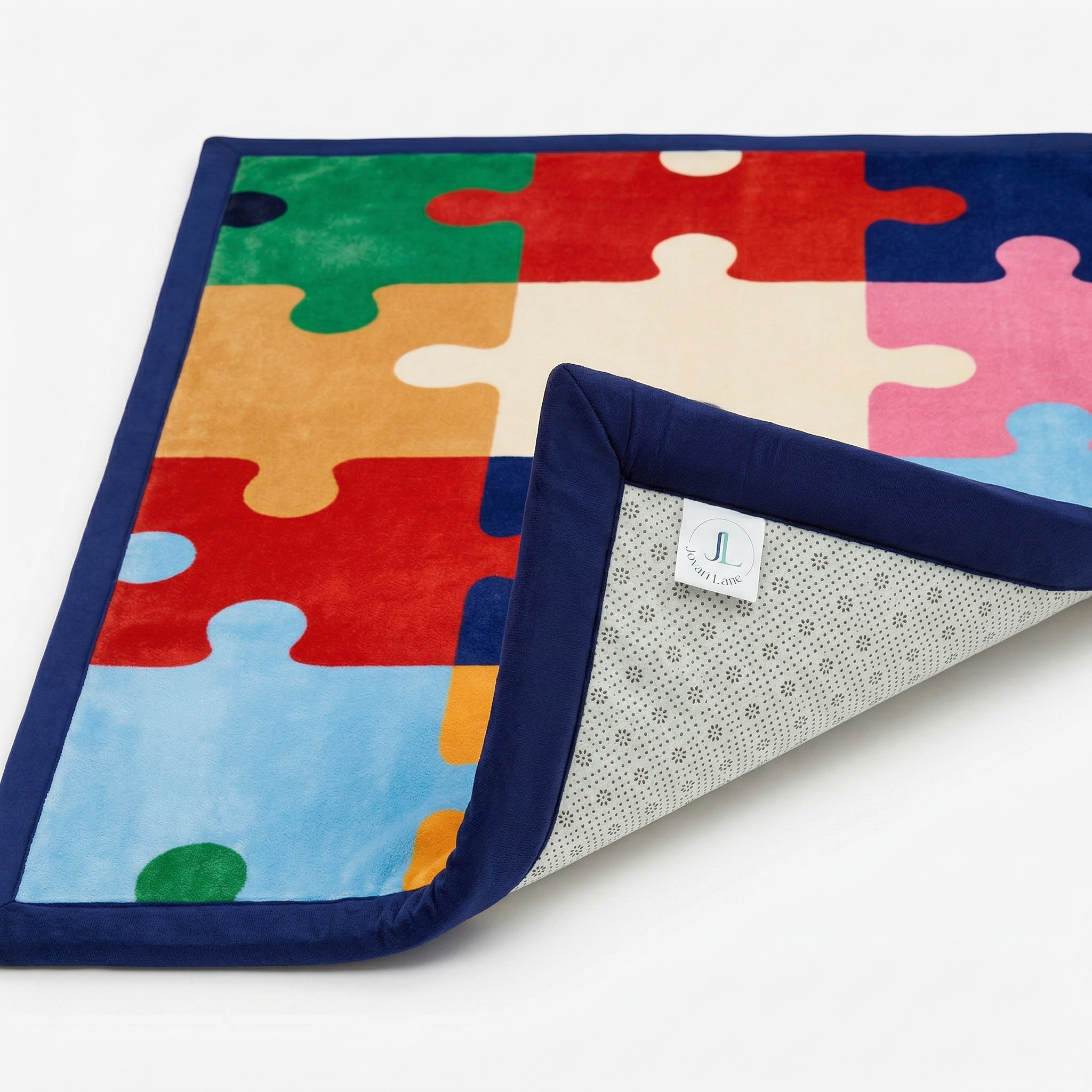 Colorful puzzle-themed blanket with a folded corner on a white background
